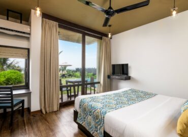 Curtain opened ,sea view bedroom with a TV, Ceiling fan, AC and other amenities.