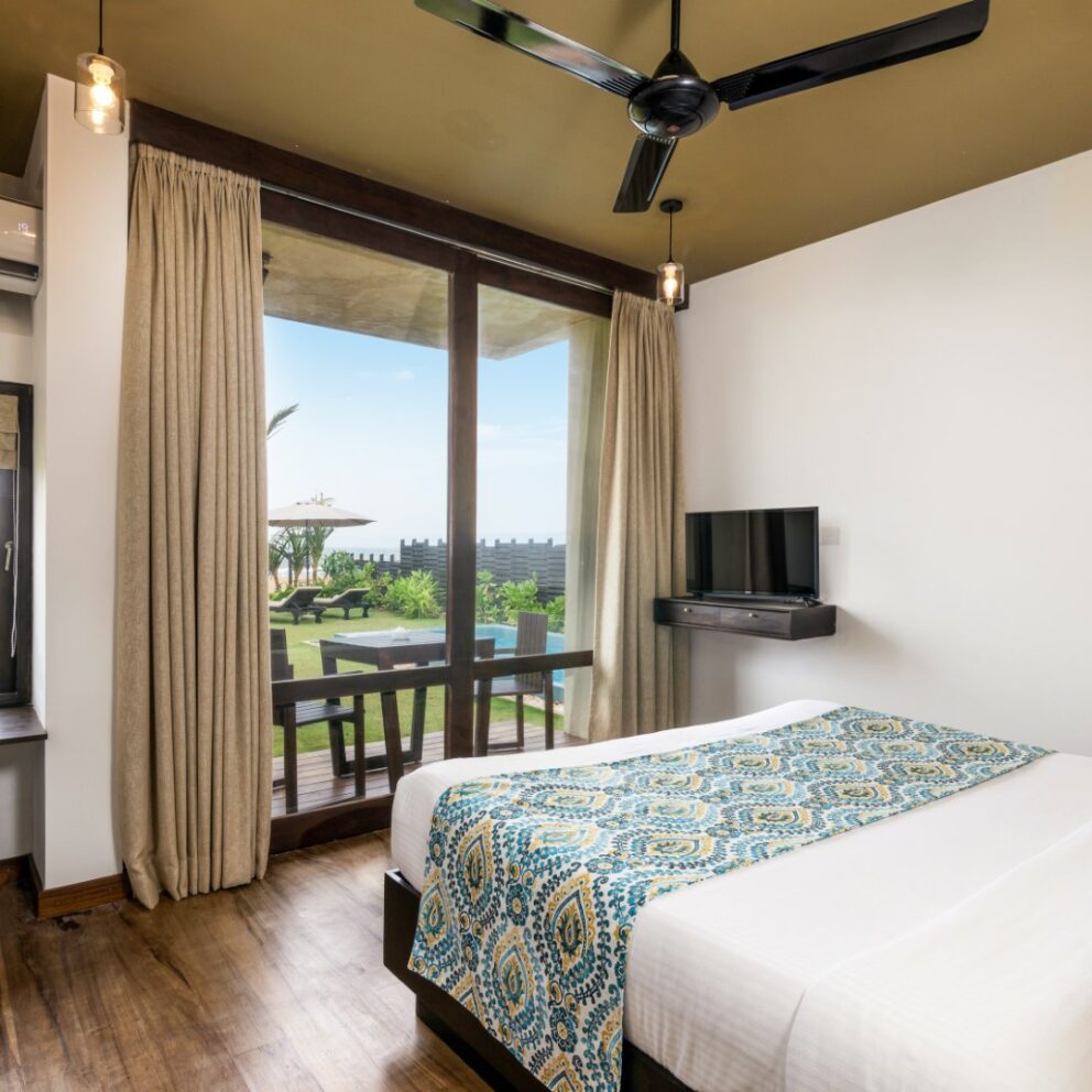 Curtain opened ,sea view bedroom with a TV, Ceiling fan, AC and other amenities.