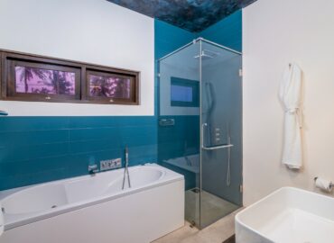 White and blue color bathroom with a bathtub, shower cubicle and a bathrobe