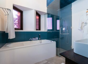 White and blue color bathroom with a bathtub, shower cubicle and a bathrobe