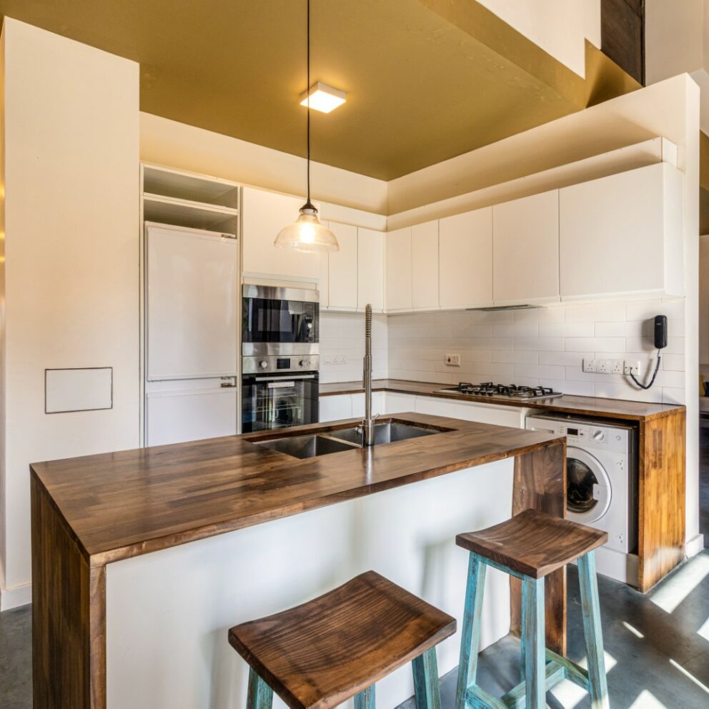 Well equipped kitchen inside the villa with a white color pantry and wood top service and cleaning area